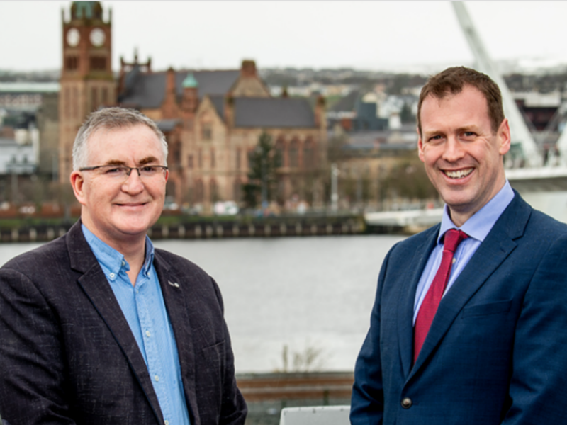 Two smartly dressed men standing beside a bridge in Derry.