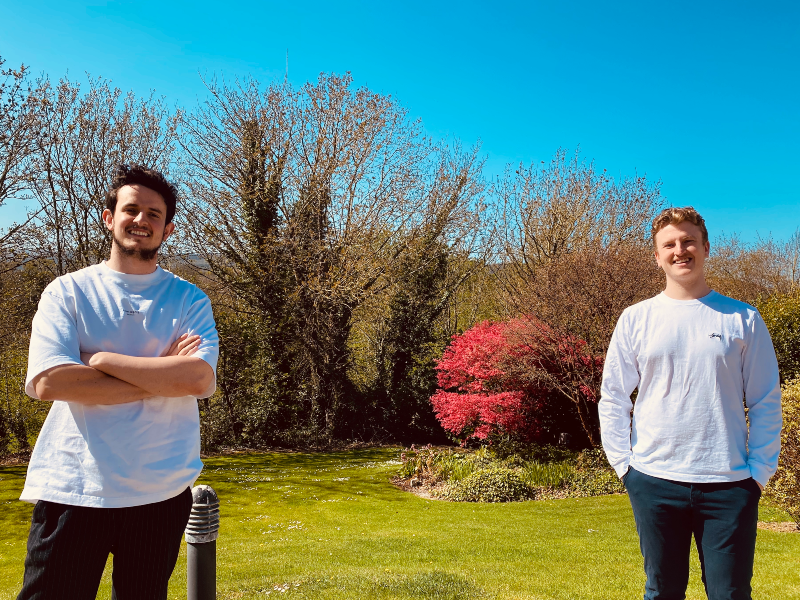 Two young men standing in a garden.
