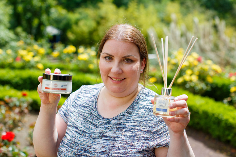Woman in garden holding a candle and diffuser.