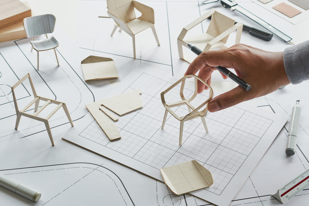 Designer with 3D printed models of chairs.