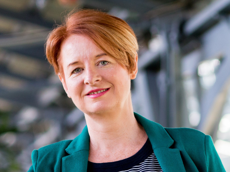 Red-haired woman wearing a green jacket.