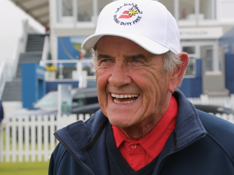 Smiling man in white baseball cap at a golf event.