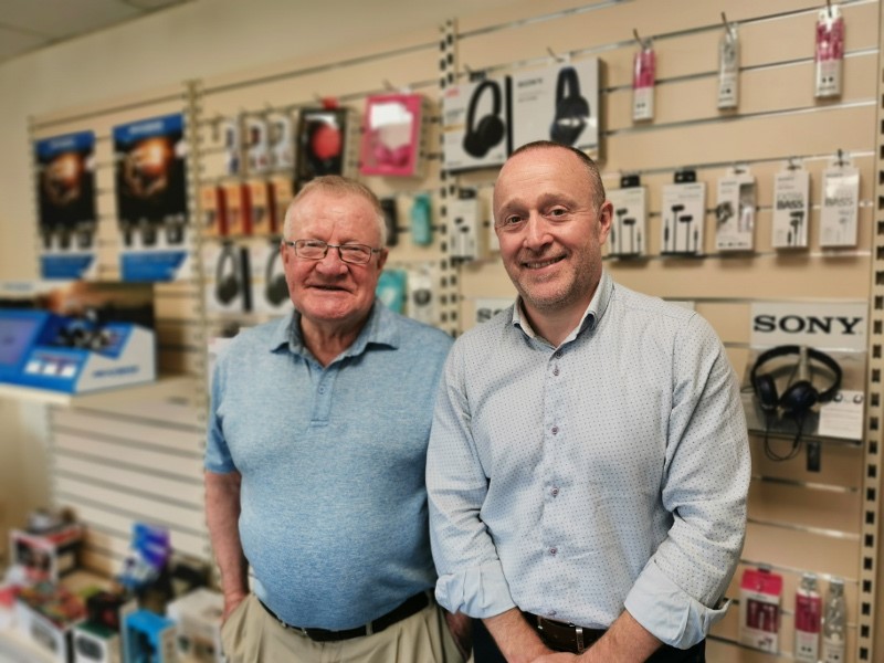 Two men, a father and a son, standing side by side.