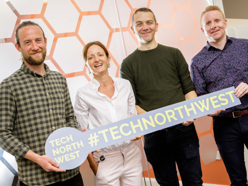 Three men and a woman hold a sign for Tech North West cluster.