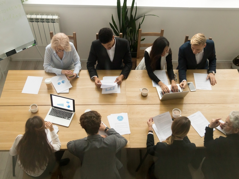 Group of people of various gender, age and ethnicity at a board meeting.