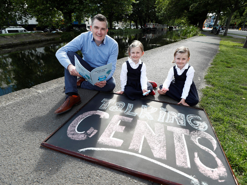 Man sitting beside canal with two young twin sisters.