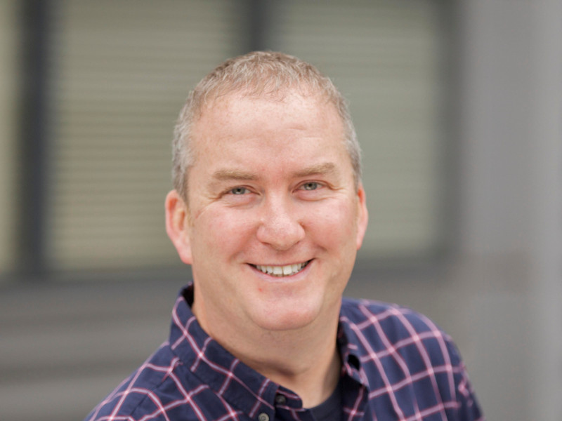 Smiling man in plaid shirt.