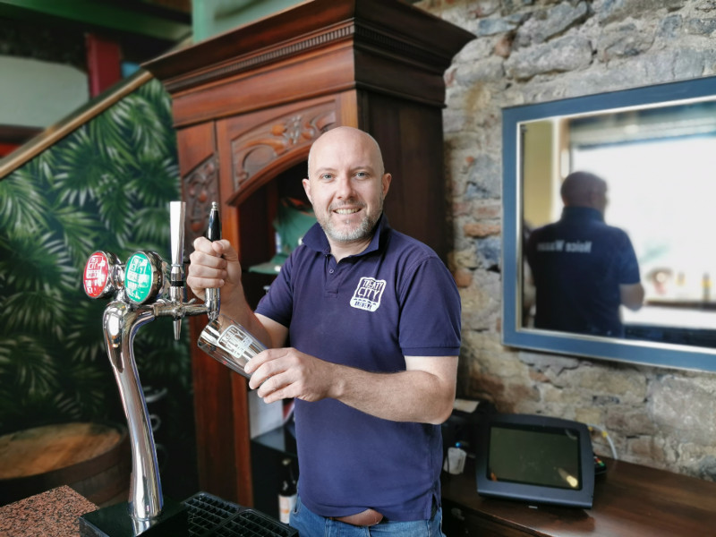 Man in blue shirt pulling a pint.