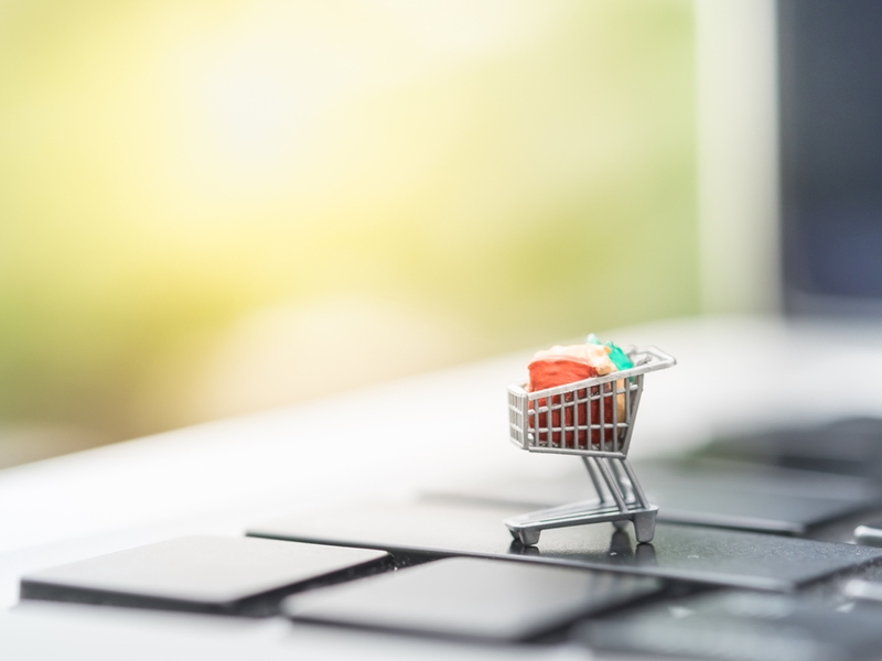 A shopping trolley filled with goods sits on top of a computer keyboard.