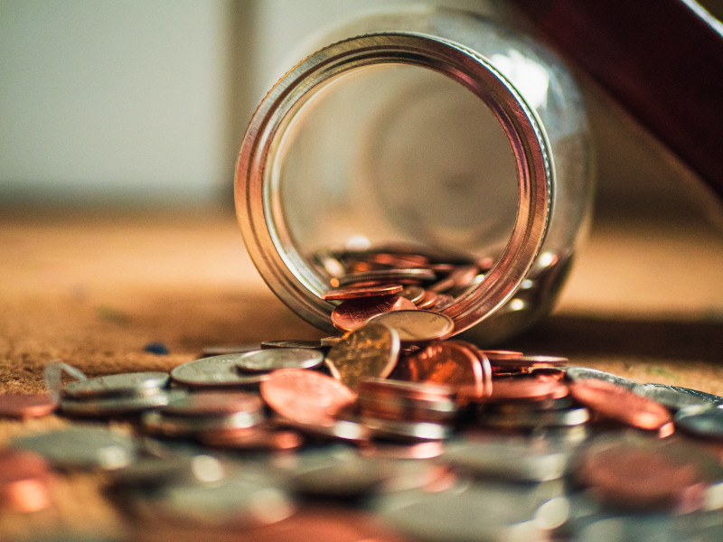 Picture of a jar on its side with coins flowing out of it.