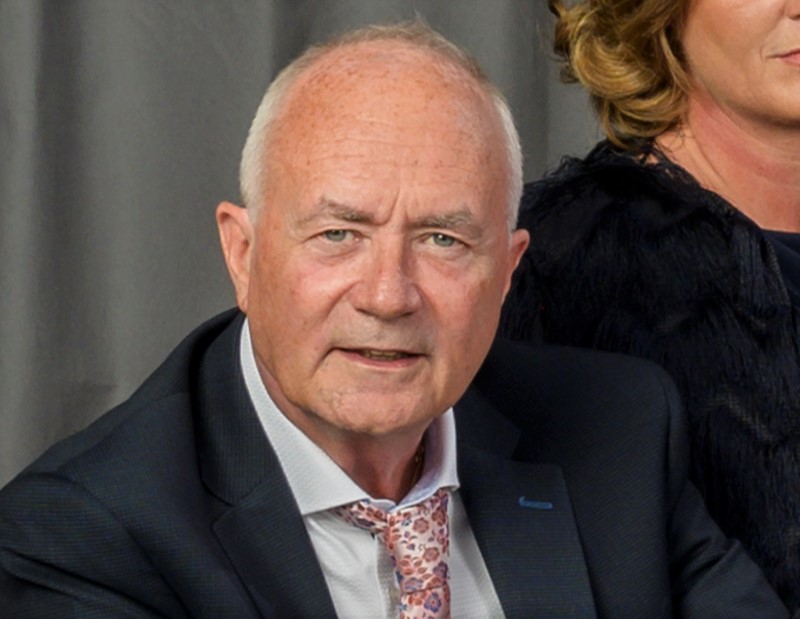 Dapper middle-aged man in dark suit and pink floral tie.