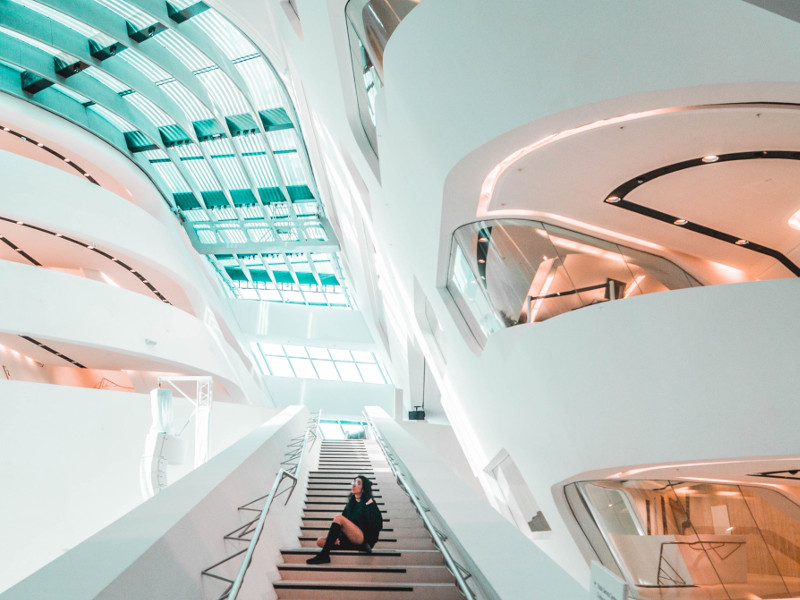 Woman sitting on a stairs in a futuristic workplace setting.