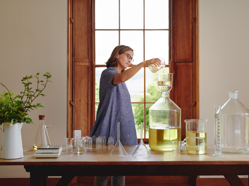 Woman pouring perfume into a giant bottle.