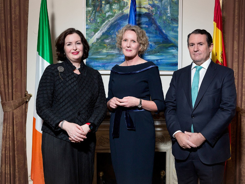 Two women in black dresses with a man in a dark suit.