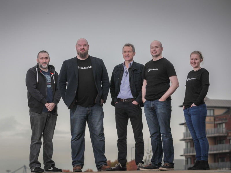 Four men and one woman standing on top of a building.