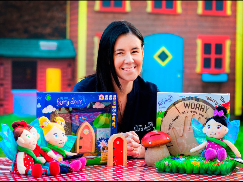 Smiling woman with black hair surrounded by toys.