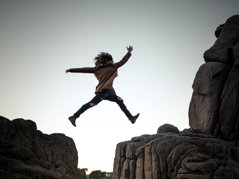 Young girl jumping across a chasm.