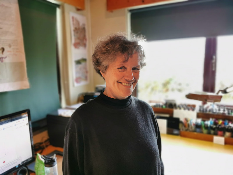 Smiling woman in black top in art studio.