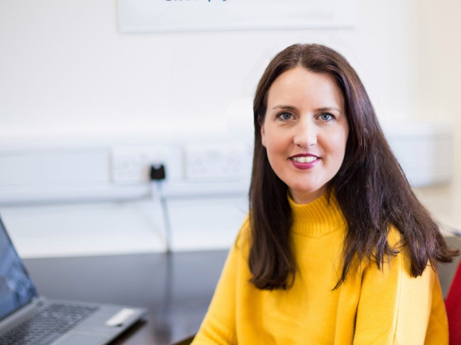 Dark haired woman in yellow jumper.