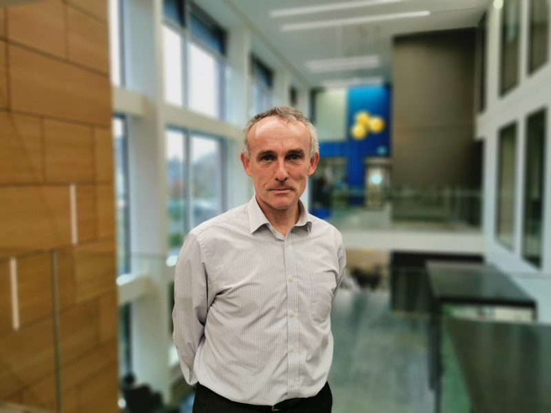 Man in white shirt standing in a building.