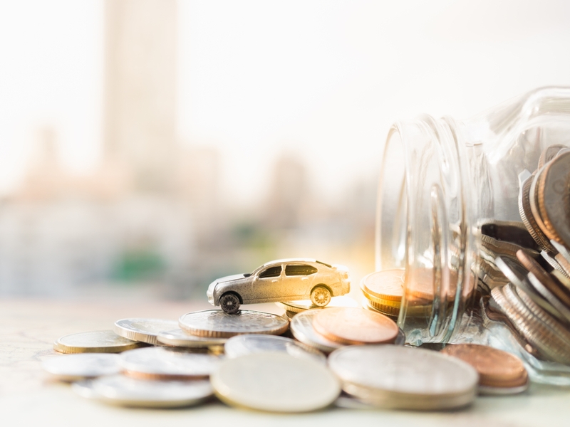 Car driving out of a jar of money.