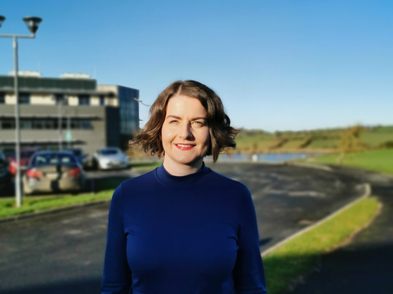 Dark-haired woman in blue dress under blue sky.