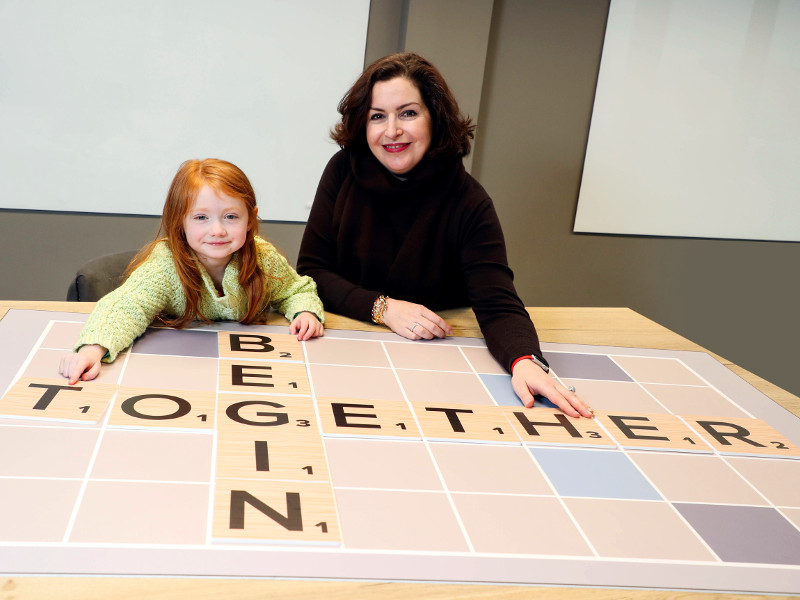 Woman in black sweater alongside young girl with red hair.