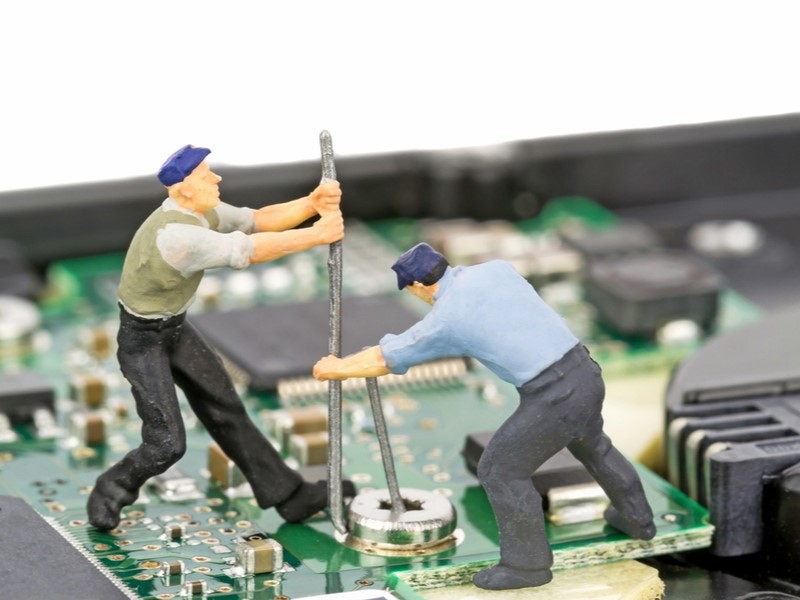 Two men digging on top of a circuit board.