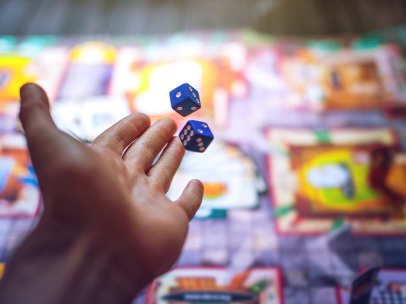 Man throws dice in board game.