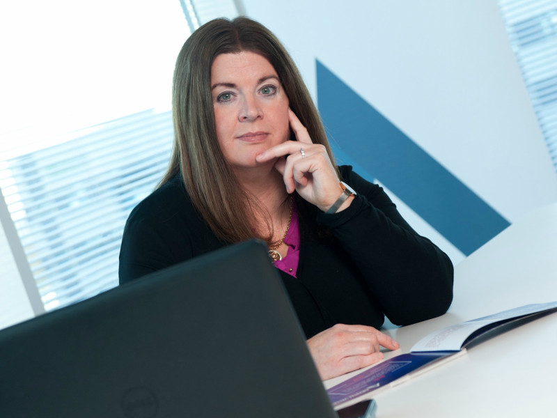 Dark-haired woman sitting in office.