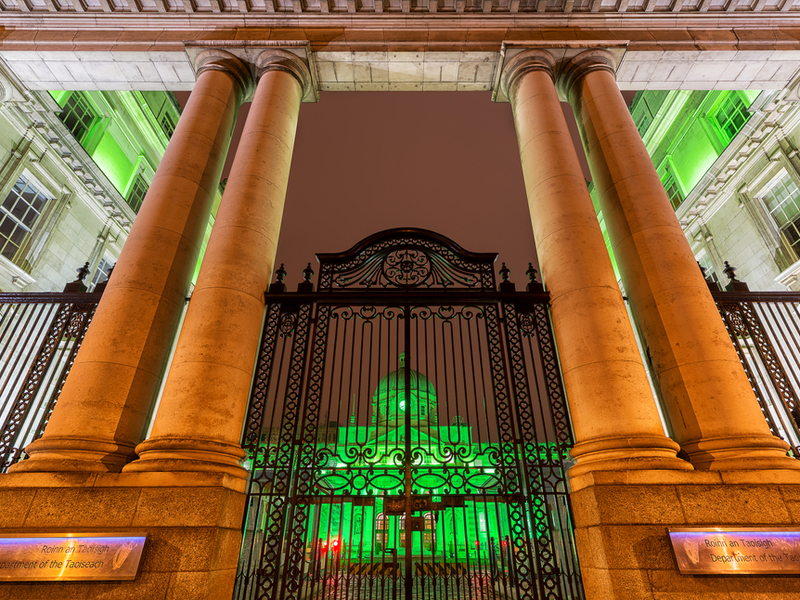 Irish Government buildings under green and orange lights.