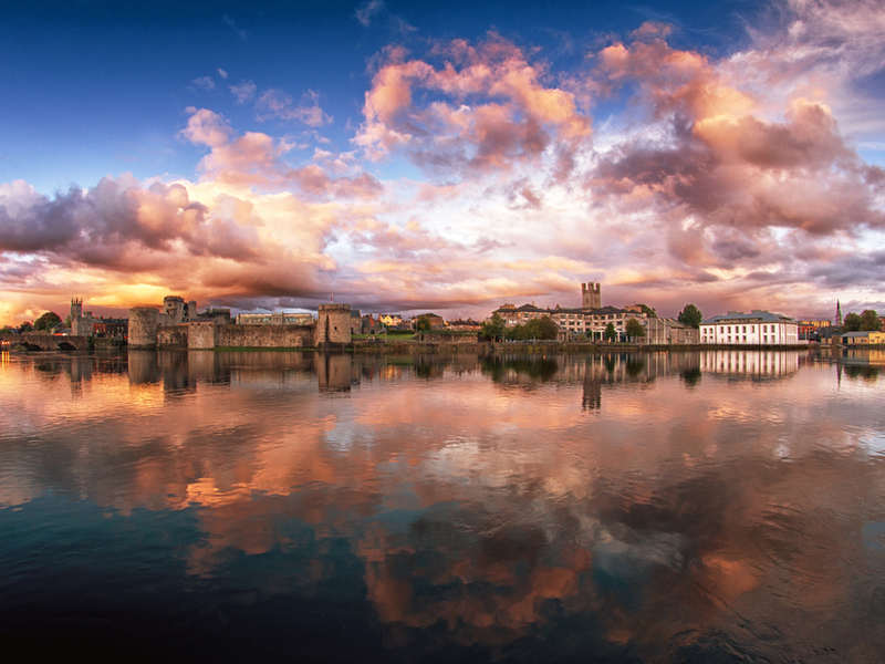 King John's Castle reflected on Shannon under a pink cloudy sky.