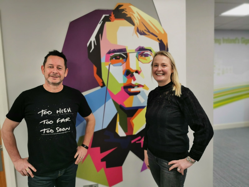 Man and woman standing in front of a mural of William Butler Yeats.