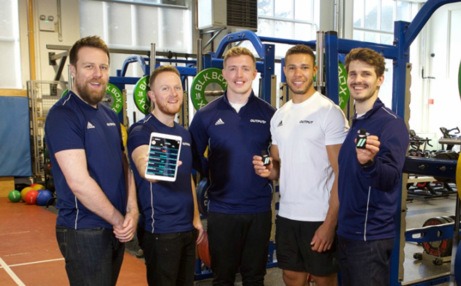 Five men standing in a gym.