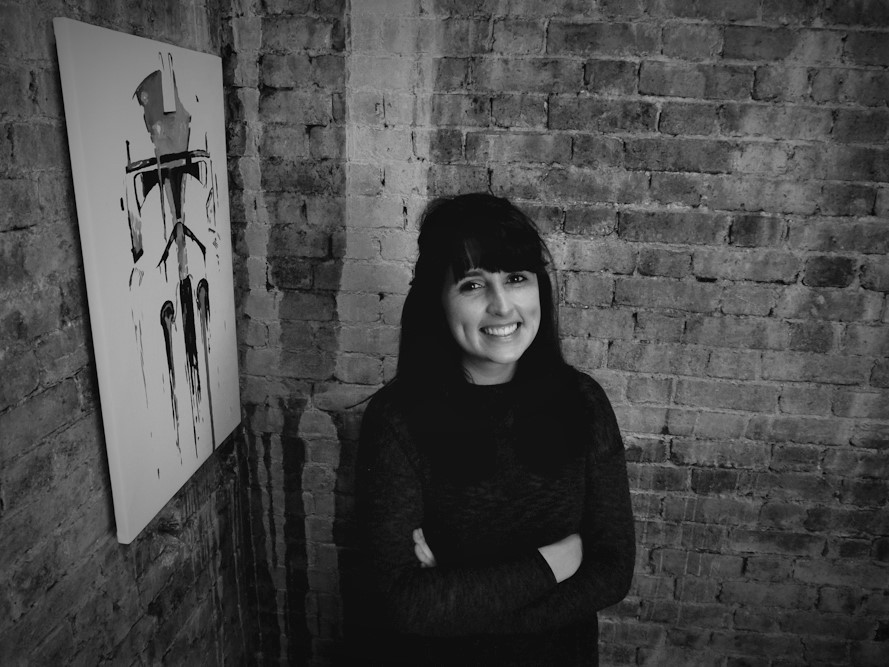 Dark-haired woman, smiling , with arms folded.