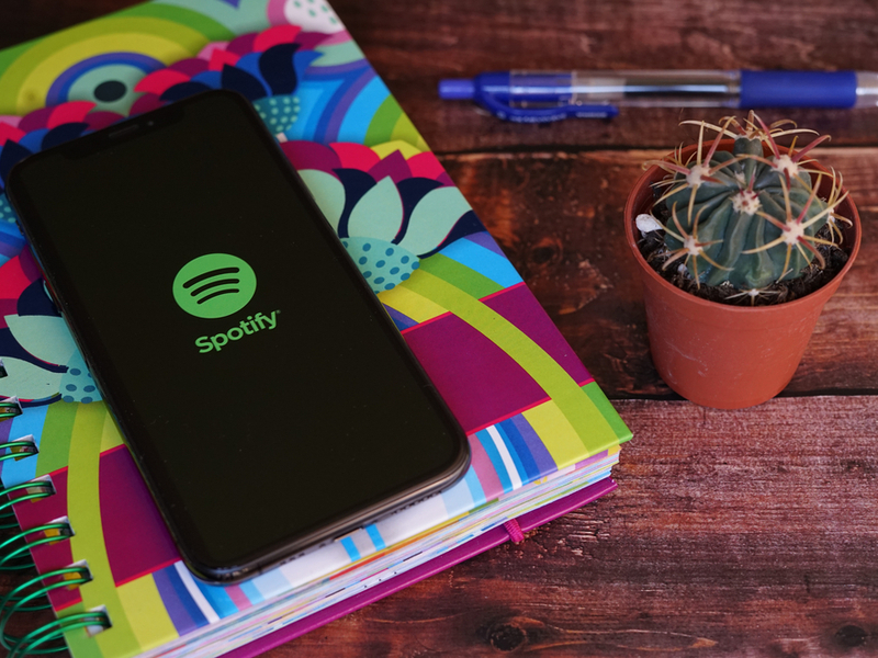 Smartphone with Spotify app on a colourful notebook with pen.