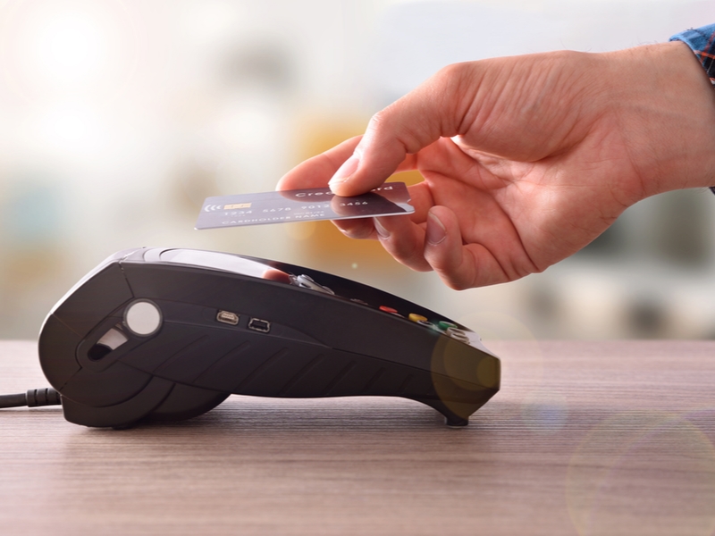 Hand making a contactless card transaction in a store.