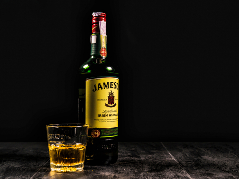 A bottle of Jameson beside a glass of whiskey.