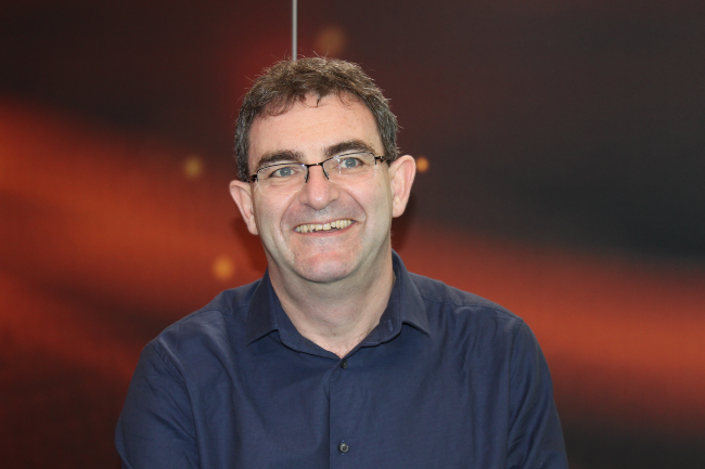 Dark-haired man with glasses in a blue shirt.