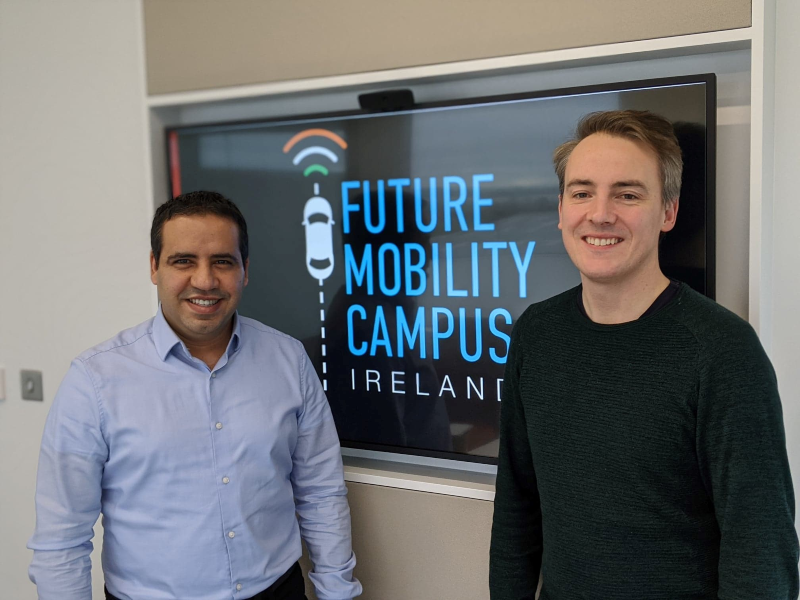 Two men standing in front of a screen saying Future Mobility Campus Ireland.