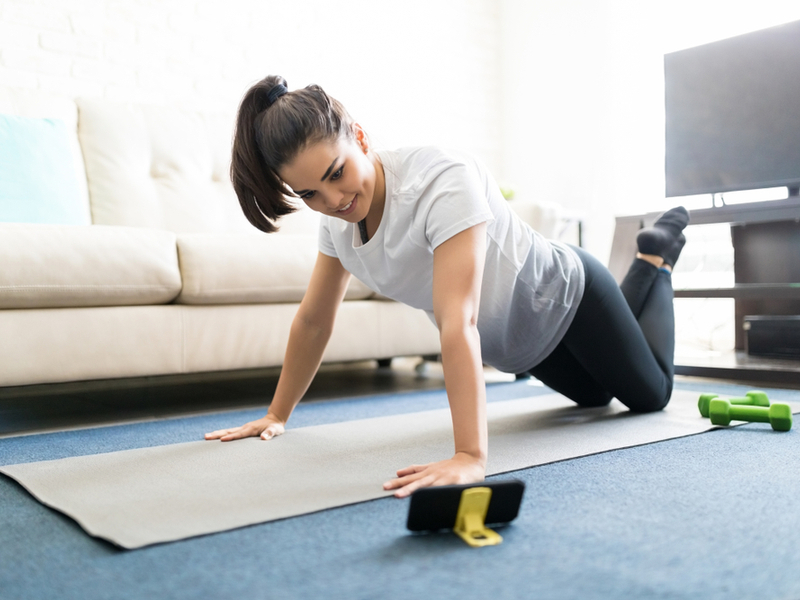 Young woman doing exercises with instructions from her smartphone.