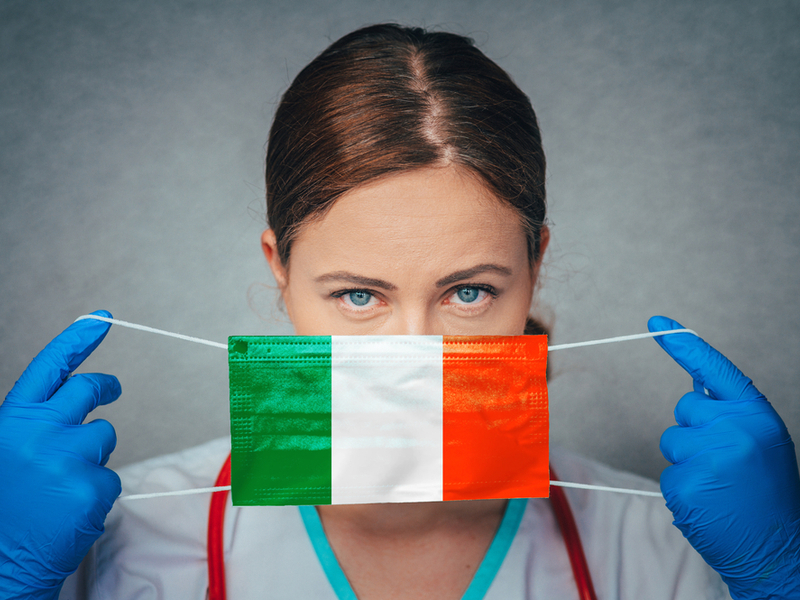 Woman with blue eyes donning a mask in colours of Irish flag.