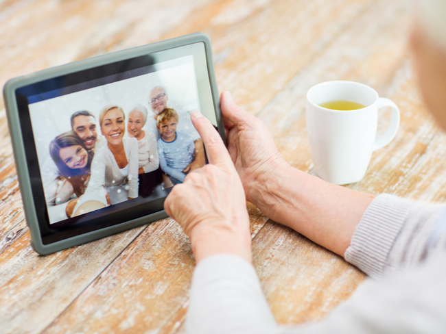 Elderly woman looking at family on a tablet computer.