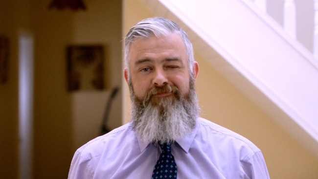 Grey-bearded man in shirt and tie.