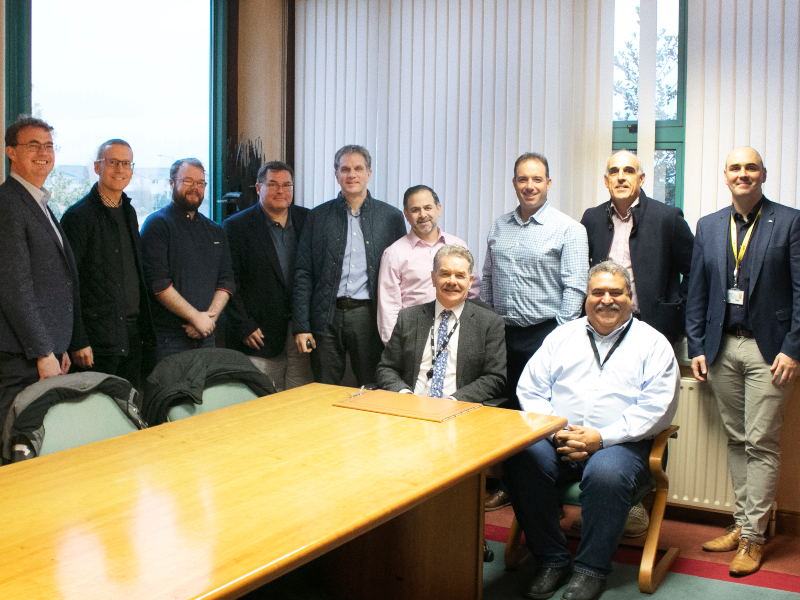 Group of men sitting and standing around a boardroom table.