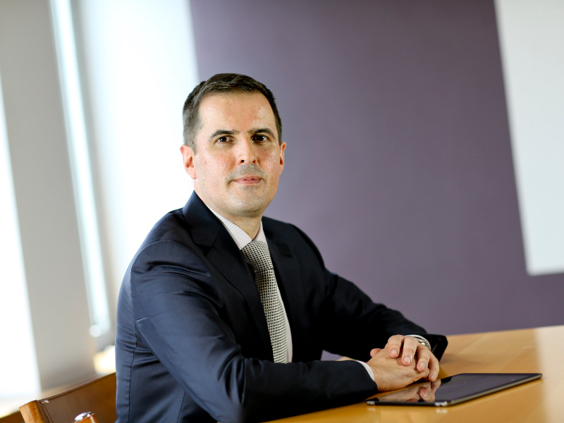 Man in navy suit sitting at table.