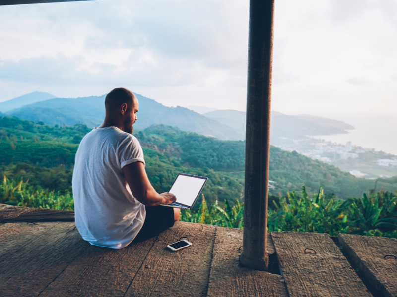 Man on laptop sitting on veranda.