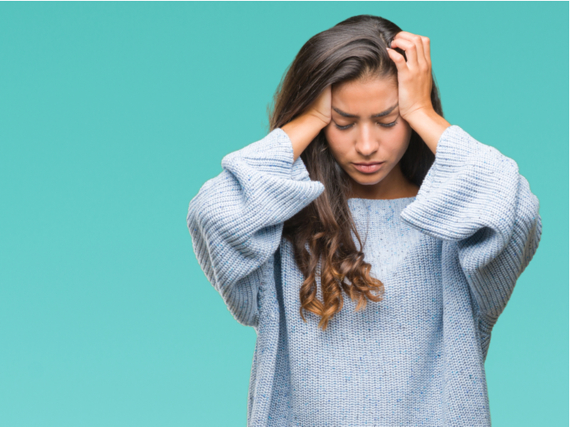 Stressed out young woman in white jumper.