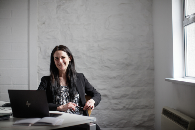 Woman at desk laughing.