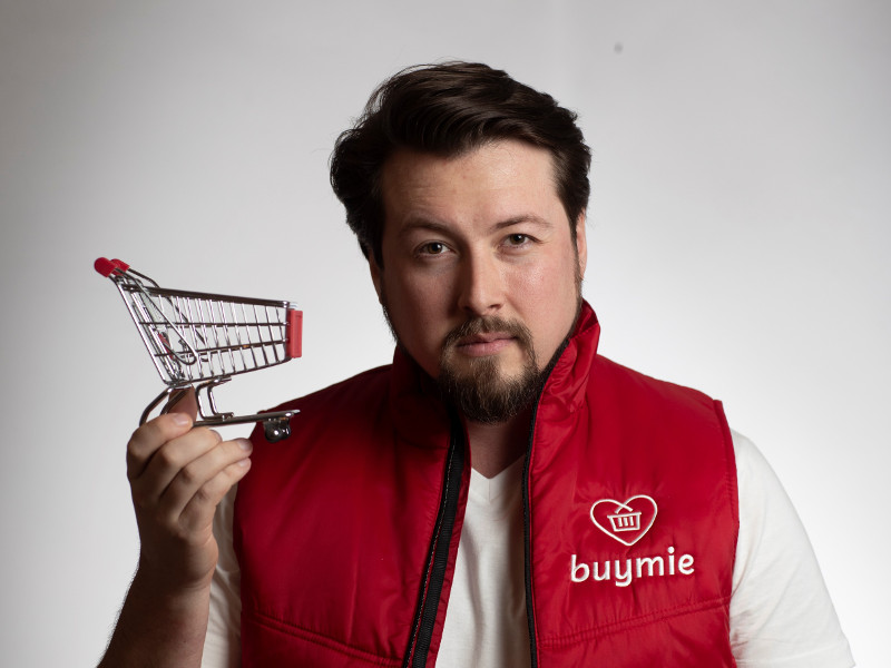 Man in red jacket holding a shopping trolley.